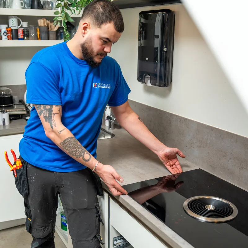 Elektricien sluit een inductiekookplaat aan in de keuken