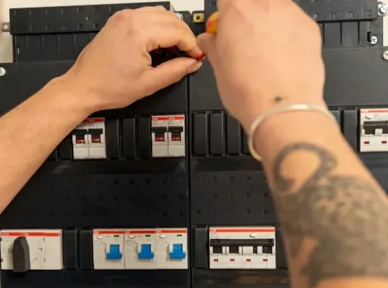 Elektricien van Louwmans werkt met een schroevendraaier aan de automaten in een groepenkast